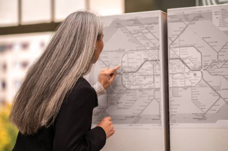 Photo for Map in a subway. Mature woman looking for a place of destination on a map in subway - Royalty Free Image