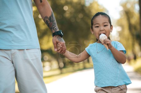Photo for Together with dad. Little girl holding her dads hand and eating ice-cream. - Royalty Free Image
