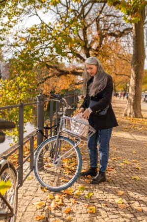 Foto de Alquilar una bicicleta. Mujer alquilando una bicicleta de calle en una calle de otoño - Imagen libre de derechos