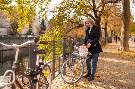 Foto de Alquilar una bicicleta. Mujer alquilando una bicicleta de calle en una calle de otoño - Imagen libre de derechos