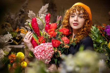 Foto de Floristería. Chica bonita en una boina naranja en una floristería - Imagen libre de derechos