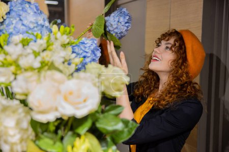 Téléchargez les photos : Fleuriste. Jolie fille dans un béret orange dans un magasin de fleurs - en image libre de droit