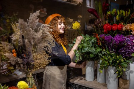 Photo for Flower shop. Pretty girl in an orange beret in a flower shop - Royalty Free Image