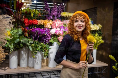 Photo for Florist at work. Cute florist in a flower shop looking enjoyed - Royalty Free Image