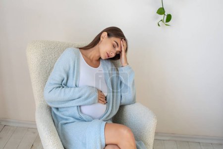 Foto de Dolor de cabeza. Mujer embarazada joven con dolor de cabeza - Imagen libre de derechos