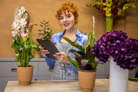 Photo for Creative mood. Cute curly-haired girl in a flower shop looking creative - Royalty Free Image