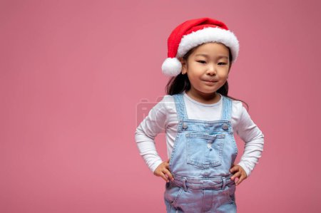 Téléchargez les photos : Noël. Petite fille mignonne en santa chapeau regardant heureux et doux - en image libre de droit