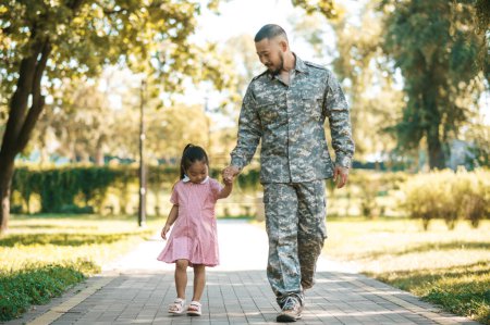 Téléchargez les photos : Week-end ensemble. Militaire marchant avec sa fille littile dans le parc - en image libre de droit