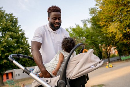 Foto de En un paseo con un niño. Joven afroamericano con su hijo en el parque - Imagen libre de derechos