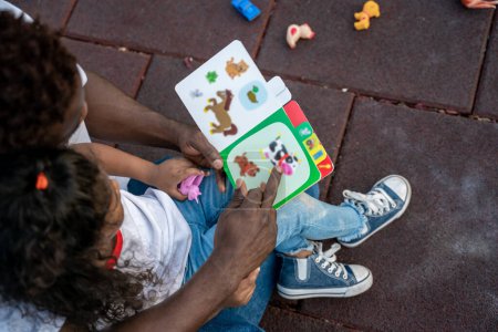 Foto de Familia feliz. Joven y una niña leyendo un libro juntos y buscando involucrados - Imagen libre de derechos
