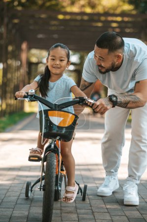 Photo for First bike. Young dad teaching his kid to ride a bike - Royalty Free Image