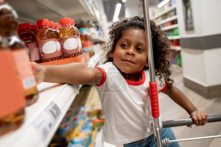 Photo for Shopping. Curly-haired cute little girl in a supermarket - Royalty Free Image