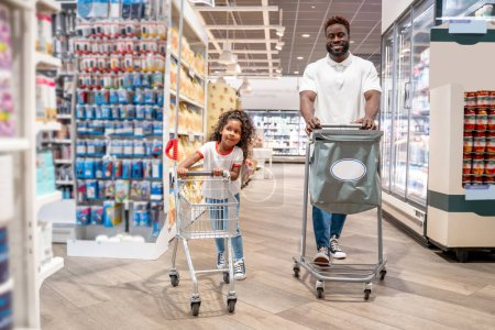 Foto de Compras de comida. Papá y su hija en una compra de alimentos en un supermercado - Imagen libre de derechos