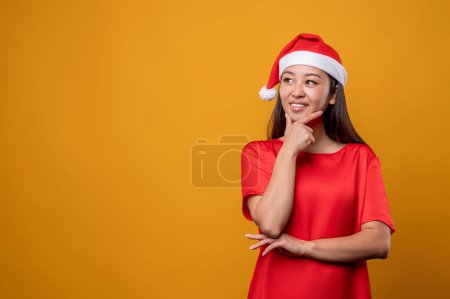 Téléchargez les photos : Dans les pensées. Jeune femme en robe rouge et chapeau de Père Noël penser à des idées de surprises - en image libre de droit