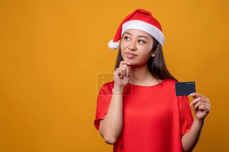 Téléchargez les photos : Les courses de Noël. Femme mignonne en robe rouge et Père Noël tenant une carte de crédit à la main - en image libre de droit
