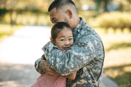 Foto de Feliz reunión. Hombre de servicio abrazando a su pequeña hija y luciendo feliz - Imagen libre de derechos