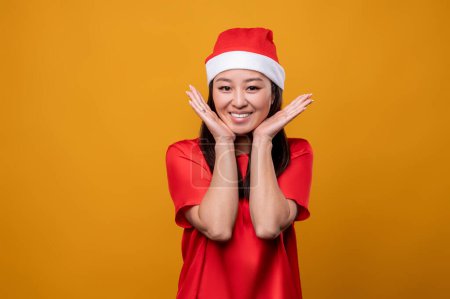 Téléchargez les photos : Joli père Noël. Mignon asiatique souriant jeune femme dans santa chapeau - en image libre de droit