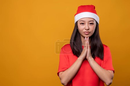 Photo for Christams prayer. Young woman in santa hat praying with her eyes closed - Royalty Free Image
