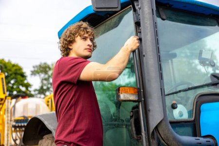 Photo for Waist-up portrait of a serious concentrated driver climbing into the tractor cab while looking into the distance - Royalty Free Image
