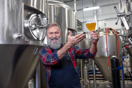 Photo for Good quality product. Brewery owner demostrating his product and looking proud - Royalty Free Image