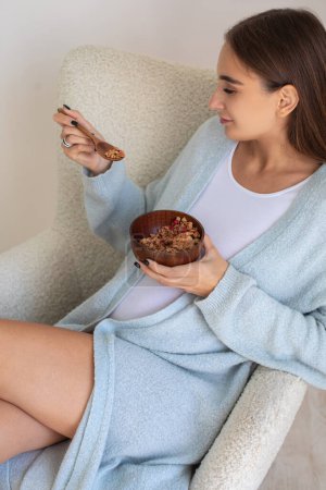 Photo for Breakfast. Young pregnant woman eating breakfast and looking enjoyed - Royalty Free Image