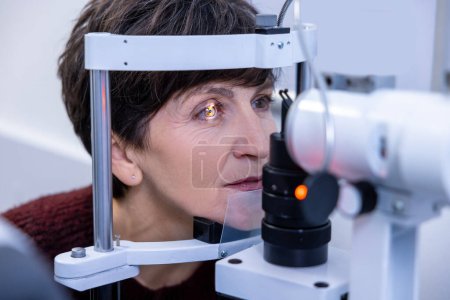 Photo for Optometry. Mid aged woman having an optometric investigation - Royalty Free Image