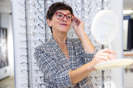 Photo for New eyeglasses. Contented mid aged woman trying on new eyeglasses - Royalty Free Image