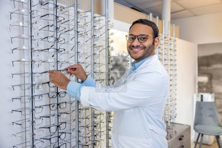 Photo for Eyeglasses for you. Smiling male consultant in lab coat selling eyeglasses - Royalty Free Image