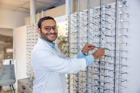 Photo for Eyeglasses for you. Smiling male consultant in lab coat selling eyeglasses - Royalty Free Image