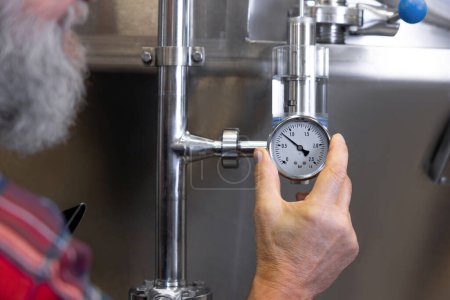 Photo for Work supervision. Brewery worker controlling the pressure in tanks with beer - Royalty Free Image