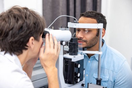 Foto de At the doctors. Female doctor examining patients eyes on the optometric equipment - Imagen libre de derechos