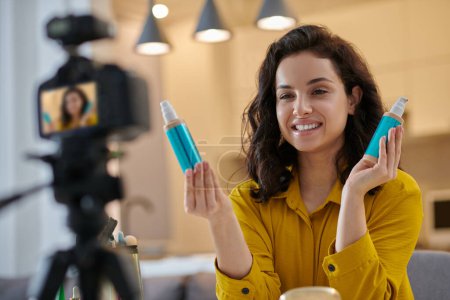 Téléchargez les photos : Beauty products. Smiling pretty young woman demonstrating new cosmetics online - en image libre de droit