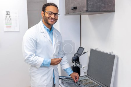 Photo for Optometrist. Male doctor in lab coat standing the box with optometric equipment - Royalty Free Image