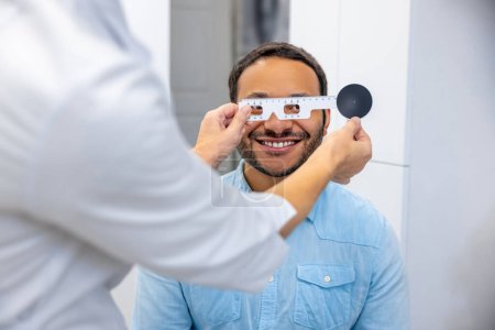 Téléchargez les photos : At the doctors. Dark-skinned smiling man having a visit to optometrist - en image libre de droit