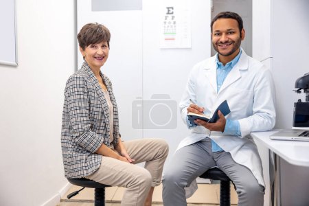 Foto de Visit to a doctor. Mid aged woman having a visti to ophtalmologist - Imagen libre de derechos