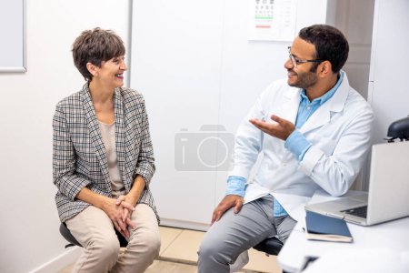 Téléchargez les photos : At the doctors. Dark-skinned doctor talking to his patient and looking friendly - en image libre de droit
