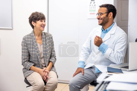 Photo for At the doctors. Dark-skinned doctor talking to his patient and looking friendly - Royalty Free Image