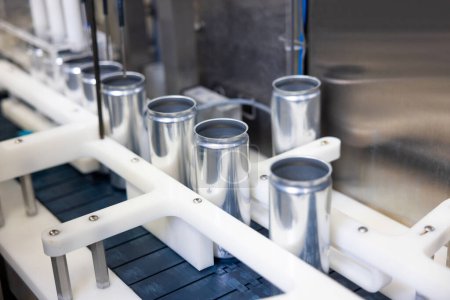 Foto de Close-up of several empty aluminum cans placed in a row on the conveyor belt of an automatic liquid filling machine - Imagen libre de derechos