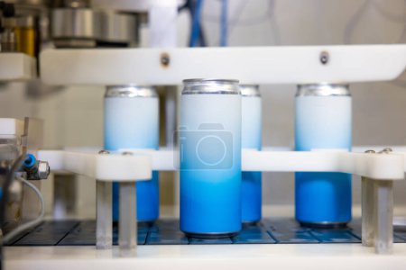 Foto de Aluminum cans arranged in a row moving on the conveyor belt of an automatic drink canning machine - Imagen libre de derechos