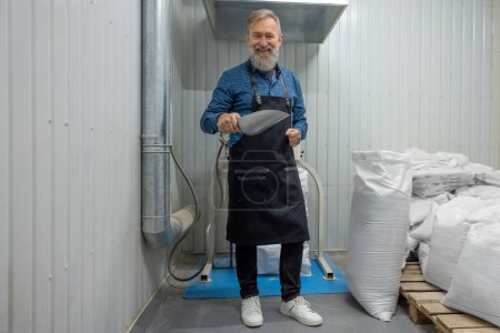 Téléchargez les photos : Working day. Mature man working in a small brewery and looking contented - en image libre de droit