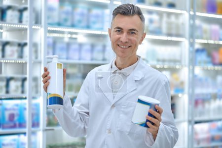 Photo for Infant milk. Smiling male pharmacist with cans of infant milk in hands - Royalty Free Image
