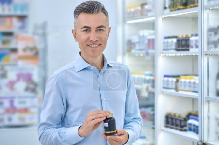 Foto de Choosing supplements. Mid aged man choosing supplements at the drugstore - Imagen libre de derechos