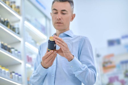 Photo for Choosing supplements. Mid aged man choosing supplements at the drugstore - Royalty Free Image