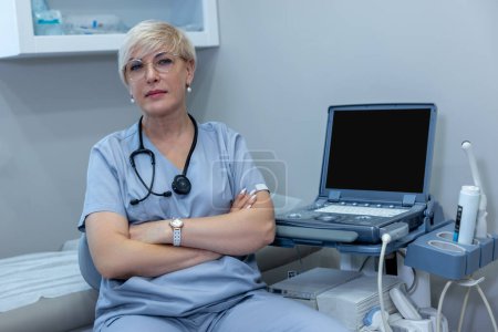 Téléchargez les photos : Gynecologist at work. emale doctor in blue scrubs sitting in the medical office - en image libre de droit