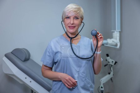 Téléchargez les photos : Gynecologist at work. Female doctor in blue scrubs sitting in the medical office - en image libre de droit