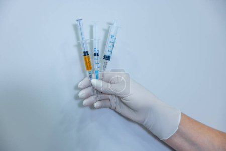 Photo for Vaccination. Close up of a hand in sterile glove holding syringes - Royalty Free Image