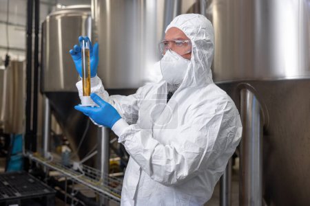 Foto de Waist-up portrait of a serious brewer holding a graduated cylinder in his hands and looking into the distance - Imagen libre de derechos