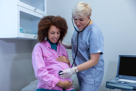 Foto de Monthly check. Obstetrician examining the pregnant woman and palping her belly - Imagen libre de derechos