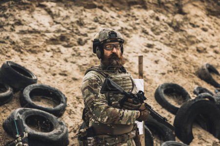 Téléchargez les photos : Soldier with rifle. Mature soldier standing near the shooting target with rifle in hands - en image libre de droit