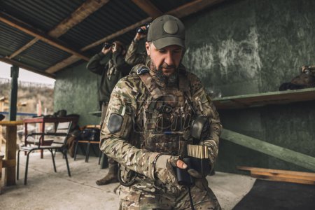 Foto de Soldier with riffle. Serious soldier in camouflage with an optical rifle - Imagen libre de derechos